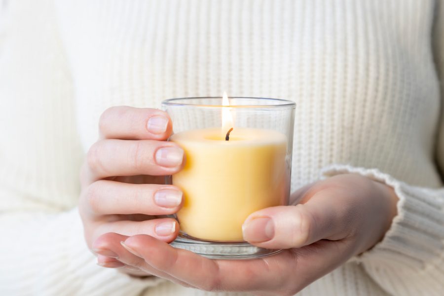 Woman holding a lit yellow scented candle