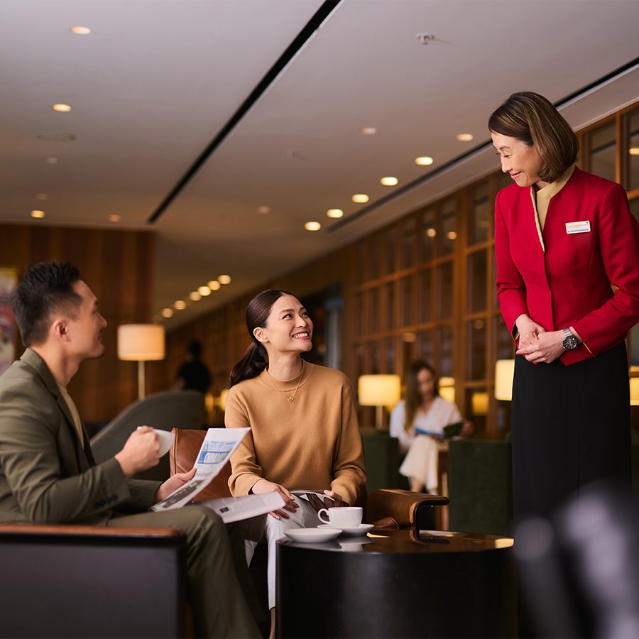 An attendant greets two guests at a Cathay Pacific airport lounge in Hong Kong 