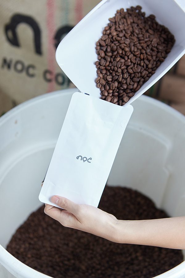 Beans being poured into an NOC coffee bag