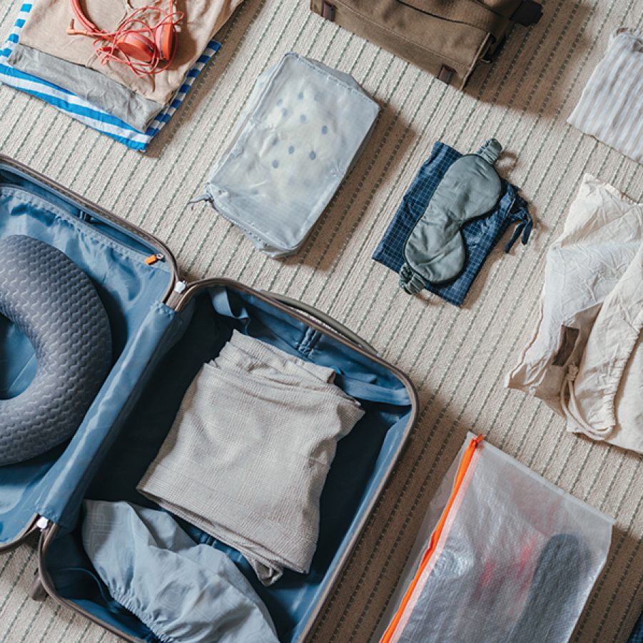 Packing the luggage with a neck pillow and loose-fit clothes