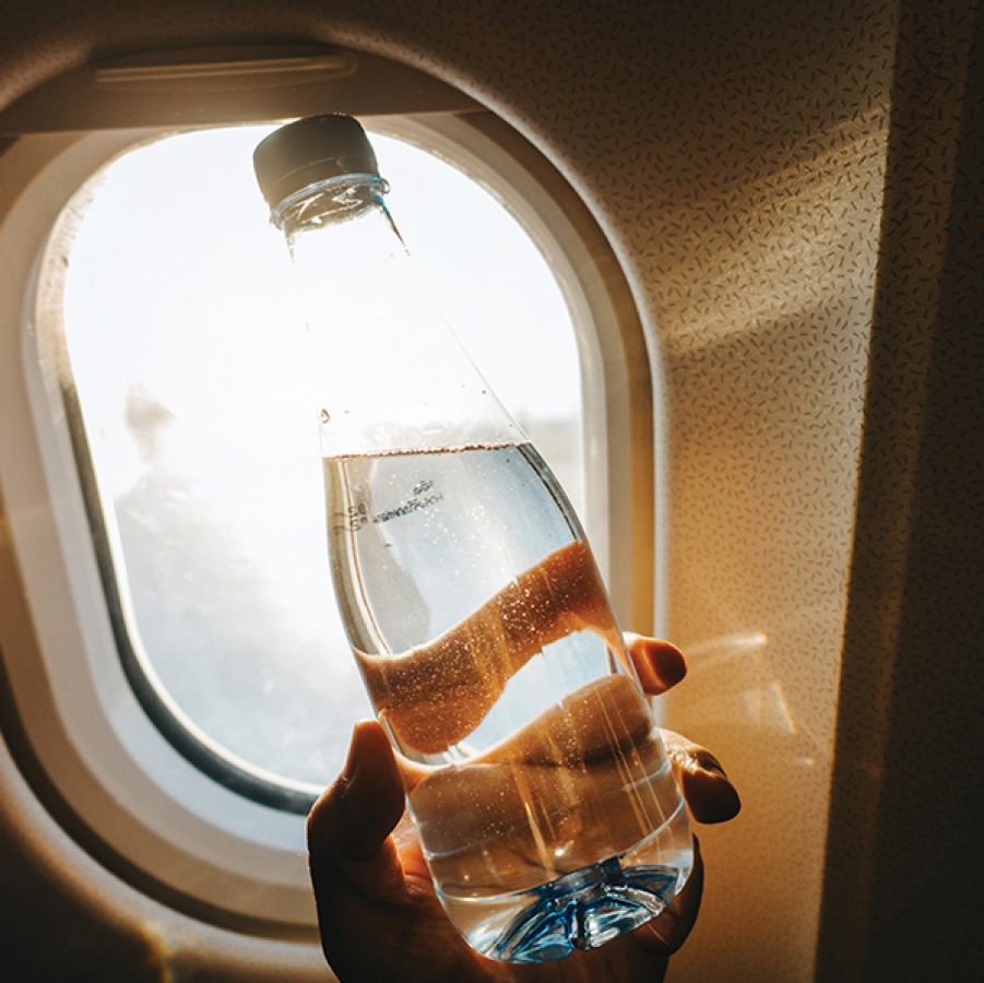 Holding a water bottle near the window on a plane
