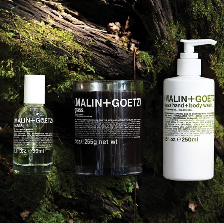 A lifestyle photo of Malin+Goetz 's grass collection - a hand and body wash, perfume and scented candle