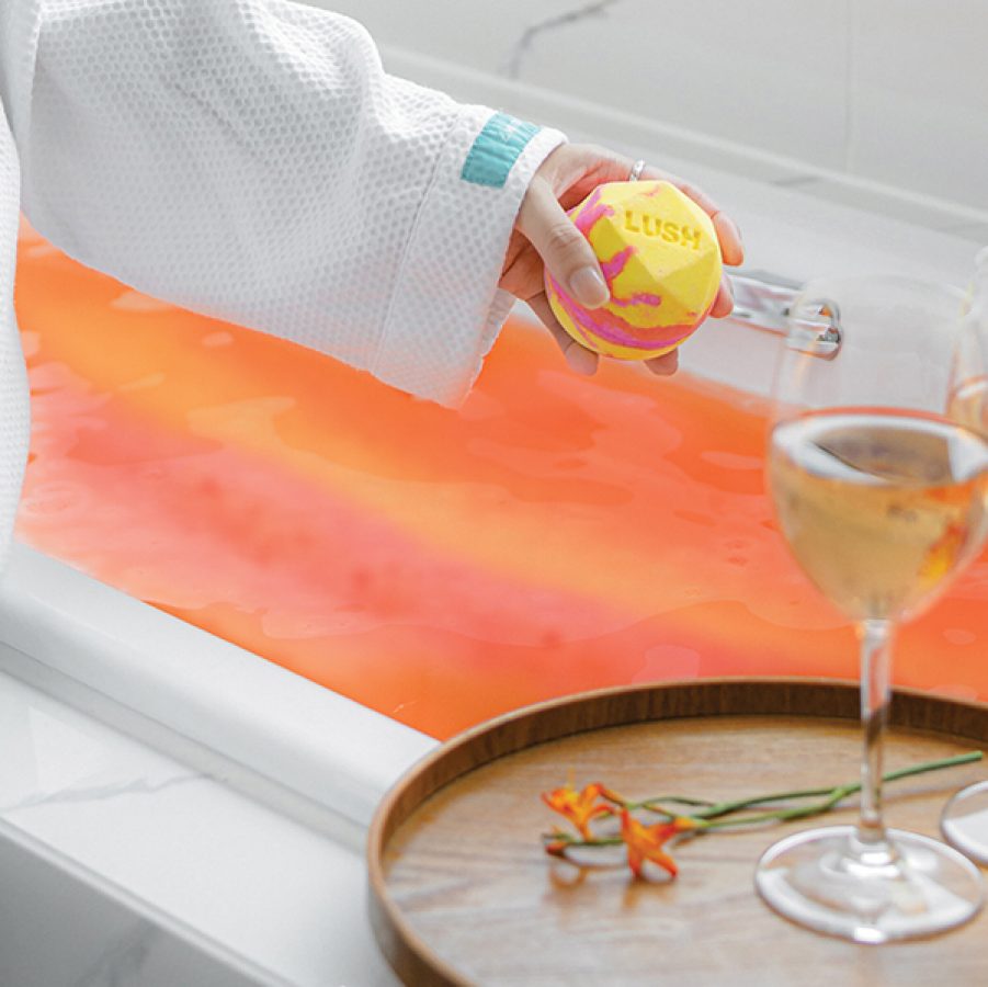 Two glasses of white wine on a tray, a person ready to take a bath.