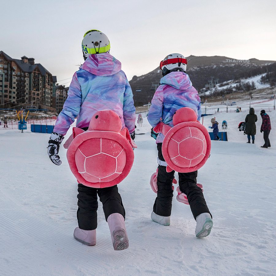 Two people wearing turtle pads walking in the snow at Thaiwoo Ski Resort in Hebei Province