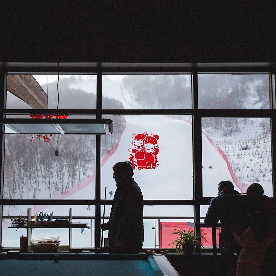 A person standing next to a window overlooking a ski slope at Yunding Ski Park in Hebei Province 