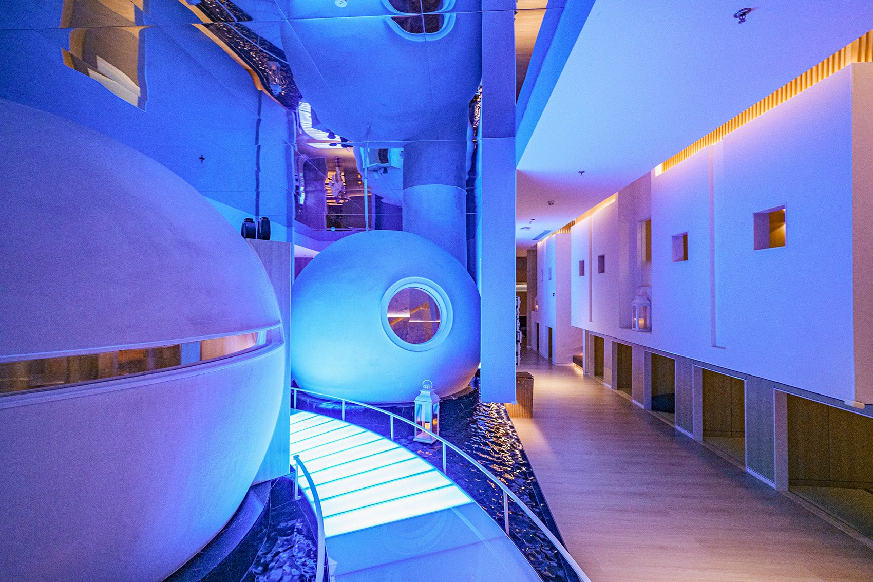 A blue-lit hallway with spherical steam rooms in Heat Joy Spa
