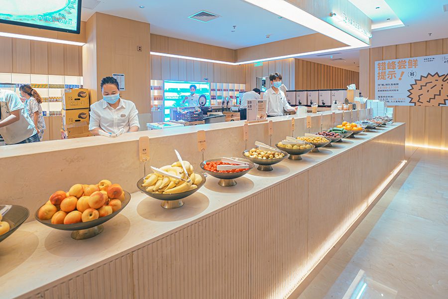 Trays of fruit lined up and staff standing behind the counter in Tangquan Life TENZ