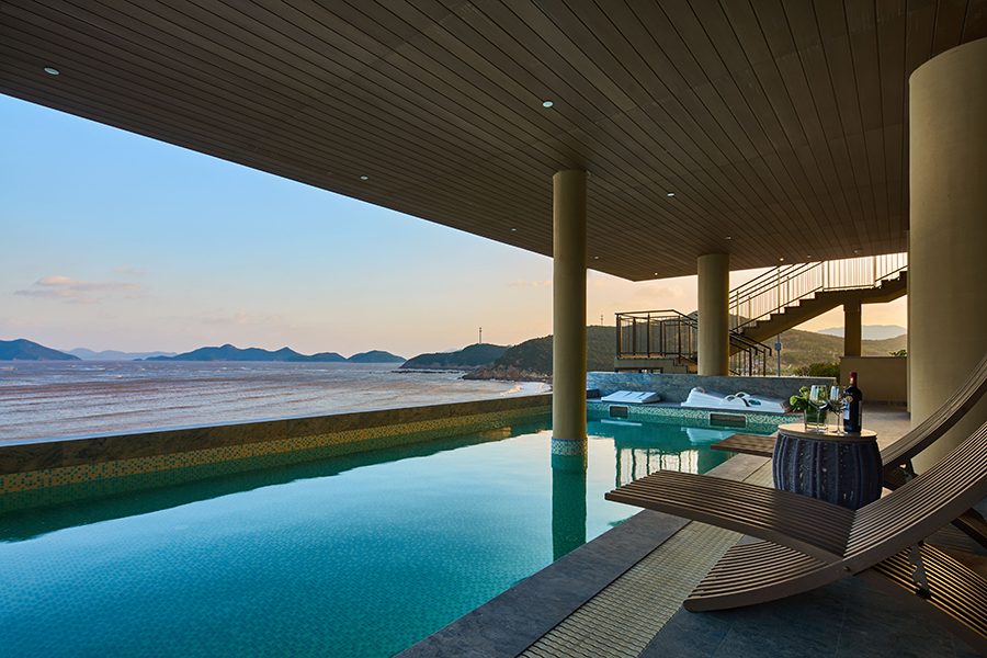 A view of the open air sheltered swimming pool facing sea views during sunset at Crown Plaza Ningbo Xiangshan Sea View hotel, China 