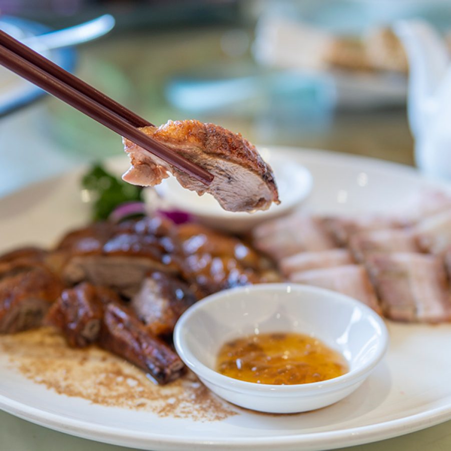 A diner holding up a piece of roast pork at a siu mei shop in Hong Kong