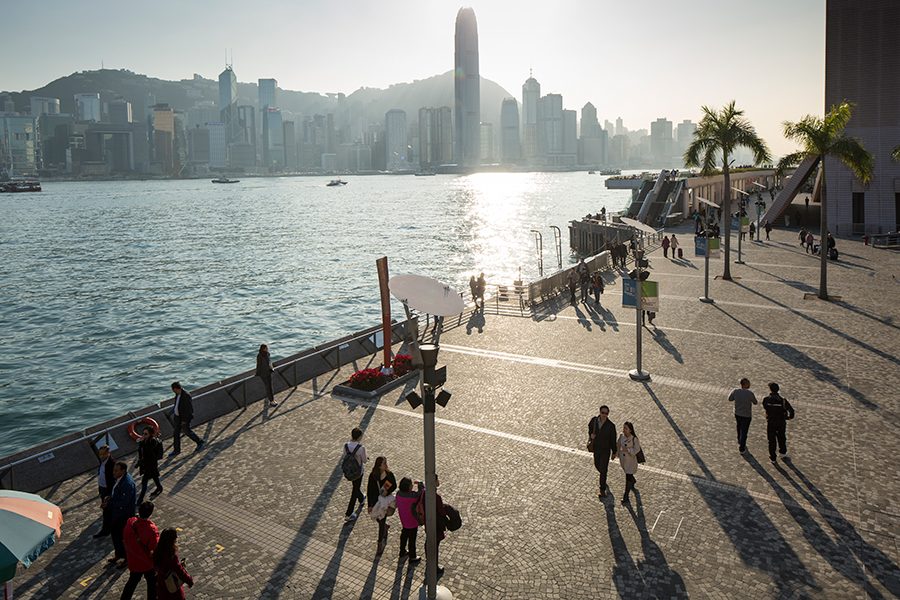 People strolling along Tsim Sha Tsui Promenade with Victoria Harbour in the background