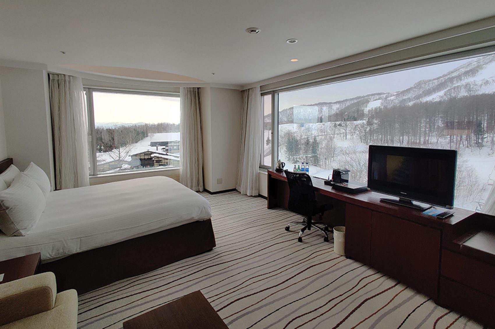 A guest room with a bed, desk and mountain view at Hilton Niseko Village