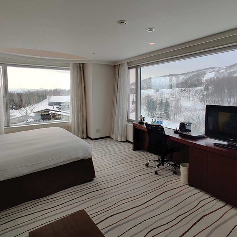 A guest room with a bed, desk and mountain view at Hilton Niseko Village