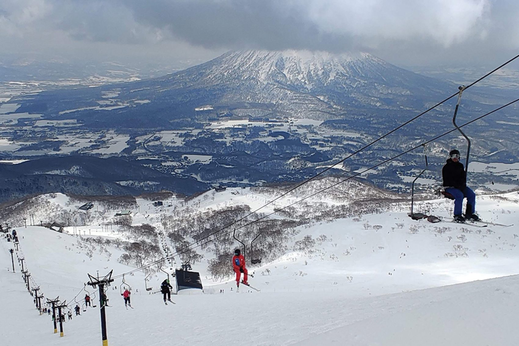 People ride a ski lift up a snowy mountain in Niseko