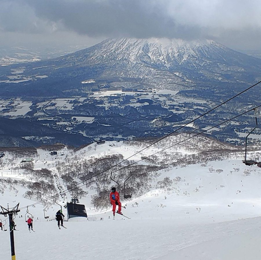 People ride a ski lift up a snowy mountain in Niseko