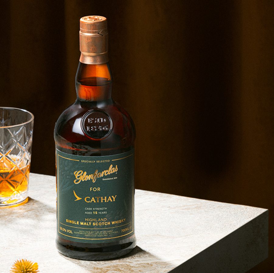 A 700mL bottle of Cathay x Glenfarclas whisky on a table next to a half-filled glass cup.
