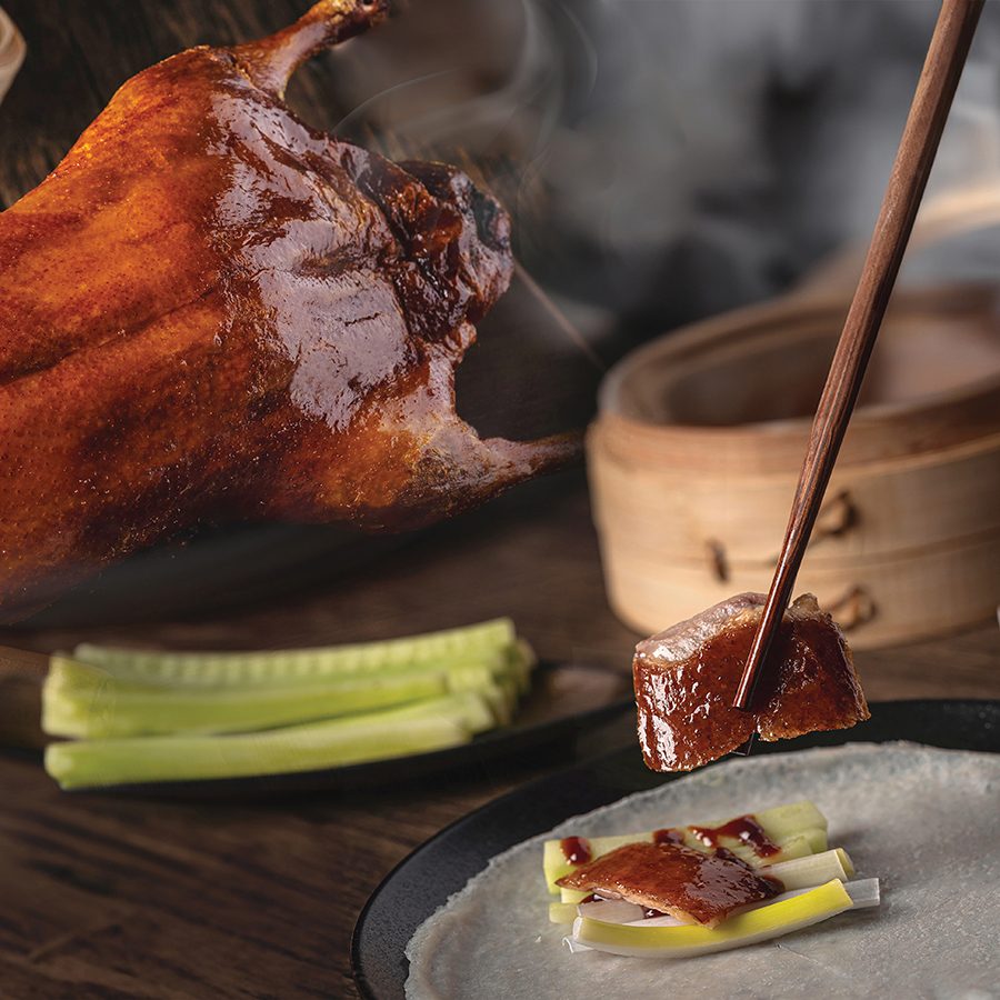 A pair of chopsticks grasping a slice of Peking roast duck at Dab-pa