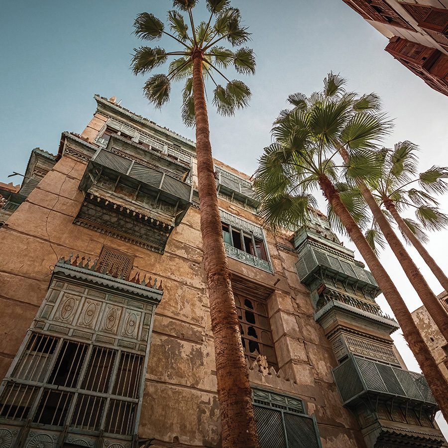 Tall palm trees next to coral-stone buildings in Al-Balad