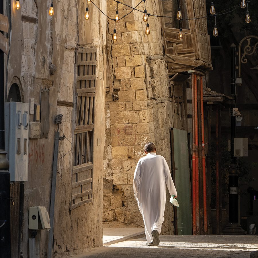 A person walking down an alleyway in Al-Balad