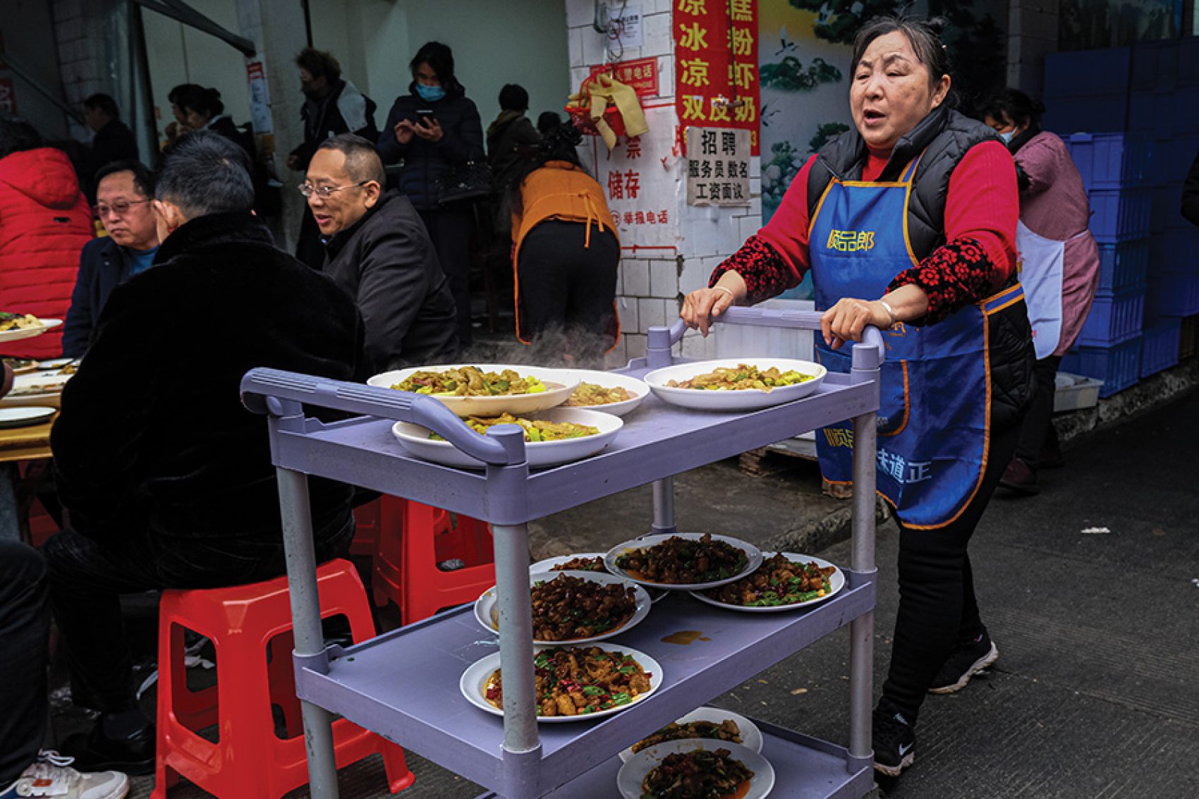 Server pushing a cart full of Sichuan dishes in Dongzikou Chenshi Liangfen, Chengdu