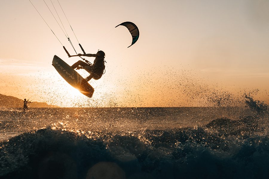 A kite-surfer in mid-air over the waves with the setting sun in the background