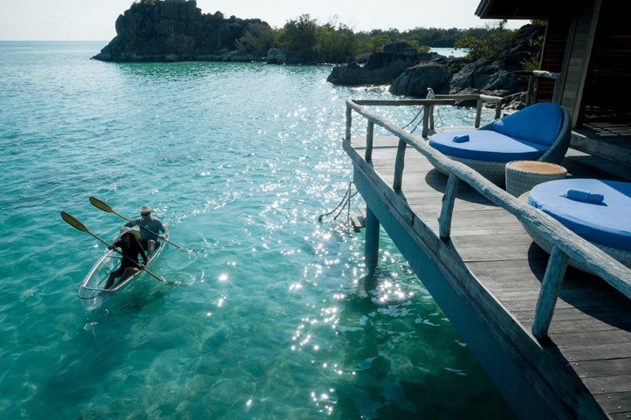 Two people in a kayak close to the edge of an overwater bungalow at Bawah Reserve, Indonesia