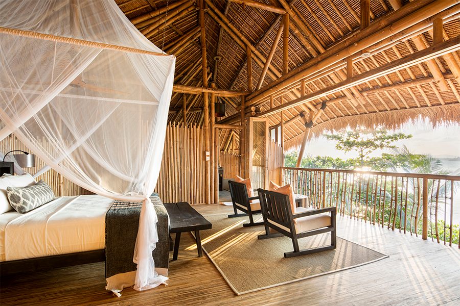 A bedroom with two chairs and a balcony overlooking the ocean at Cempedak Private Island, Indonesia