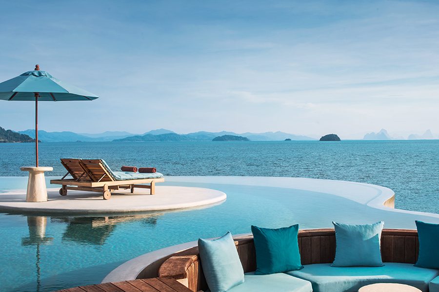 Deck chairs on a platform in an infinity pool overlooking the ocean at The Naka Island resort in Thailand.