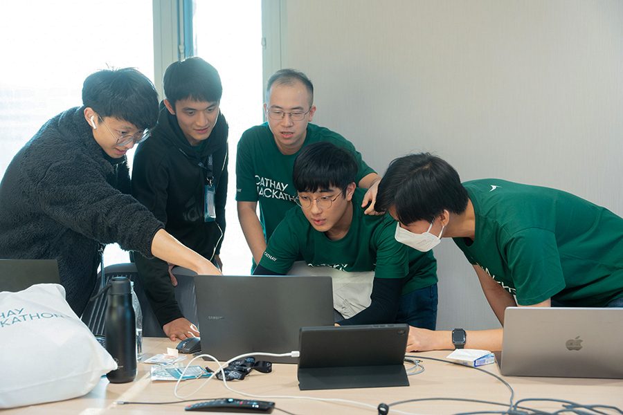 A team of participants at the Cathay Hackathon gathered around a computer