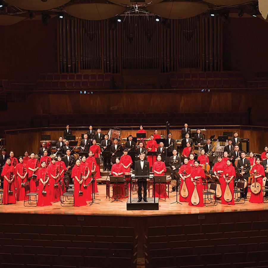 The Guangdong Chinese Orchestra standing on stage with their instruments