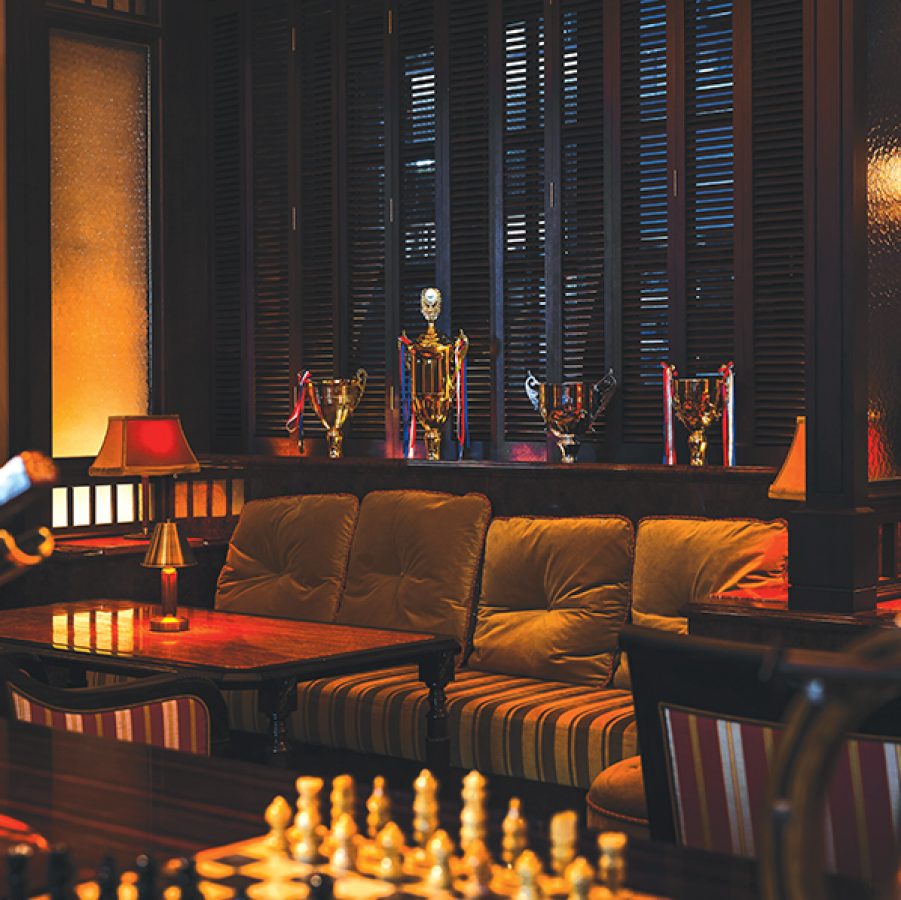  The interior of Jack’s Racquet Room, which includes a couch and coffee table, a chess board, sports trophies and a bottle of wine