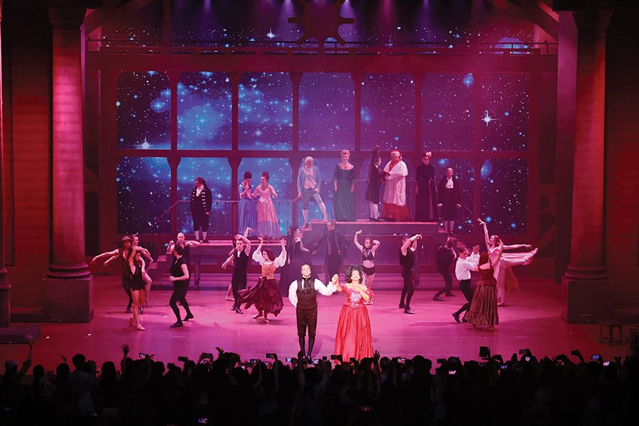 A group of people dancing on stage with reddish lighting during the musical Mozart, L’Opéra Rock