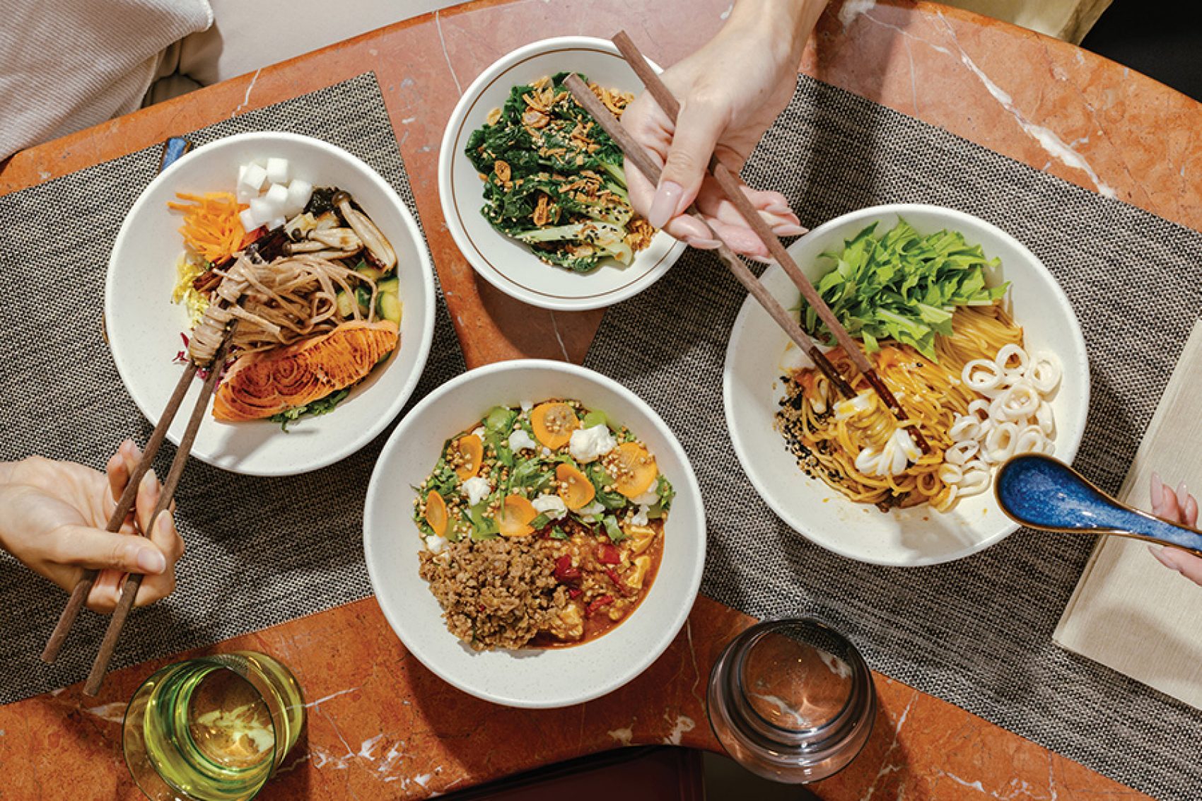 Hands holding chopsticks and a spoon over a table full of plant-forward dishes at Victuals in Basehall 02