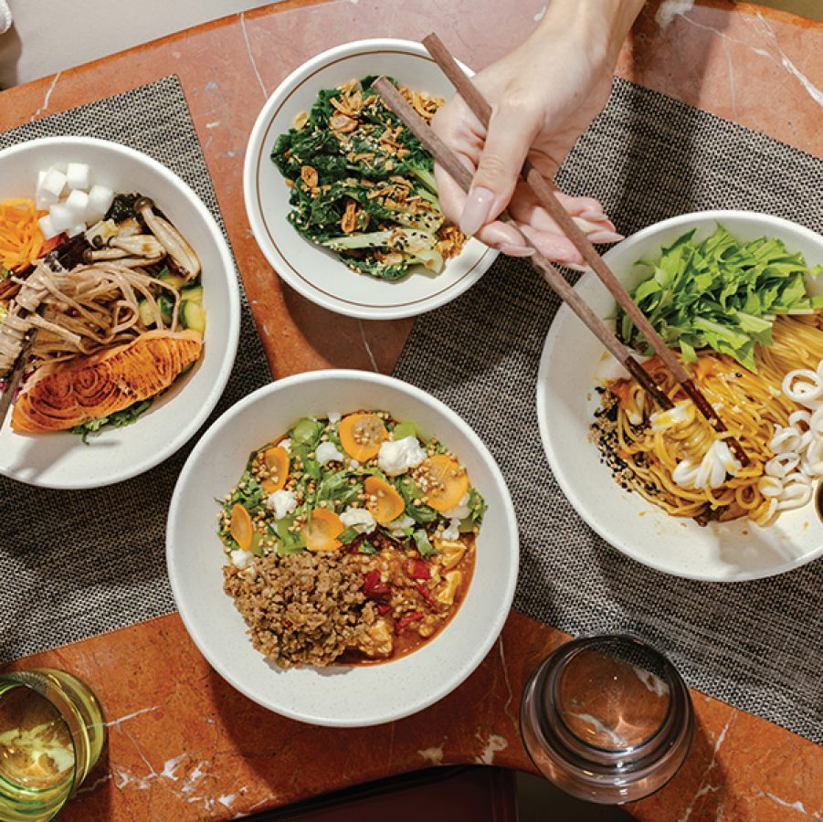 Hands holding chopsticks and a spoon over a table full of plant-forward dishes at Victuals in Basehall 02