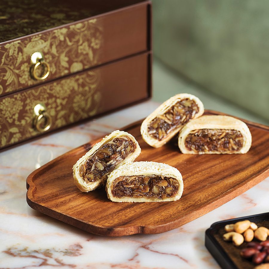 Ming Pavilion’s mooncakes displayed on a wooden board and marble surface in front of a brown drawer box