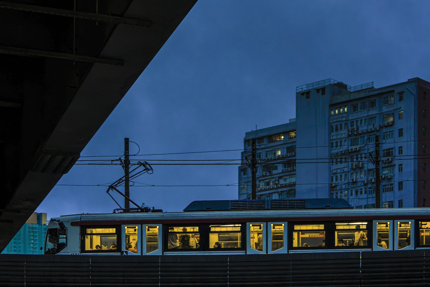 A photograph of an MTR train in front of a residential building from the exhibition Railscape Reminisce
