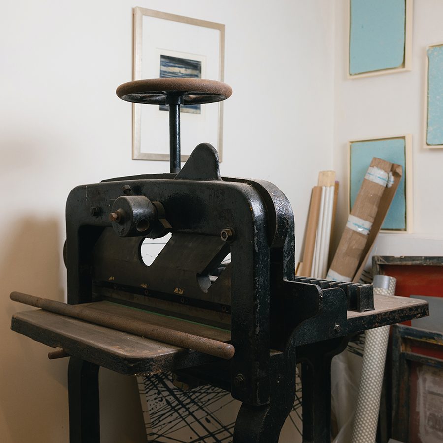 A cast iron finishing press with a round wheel crank in Percy So’s studio