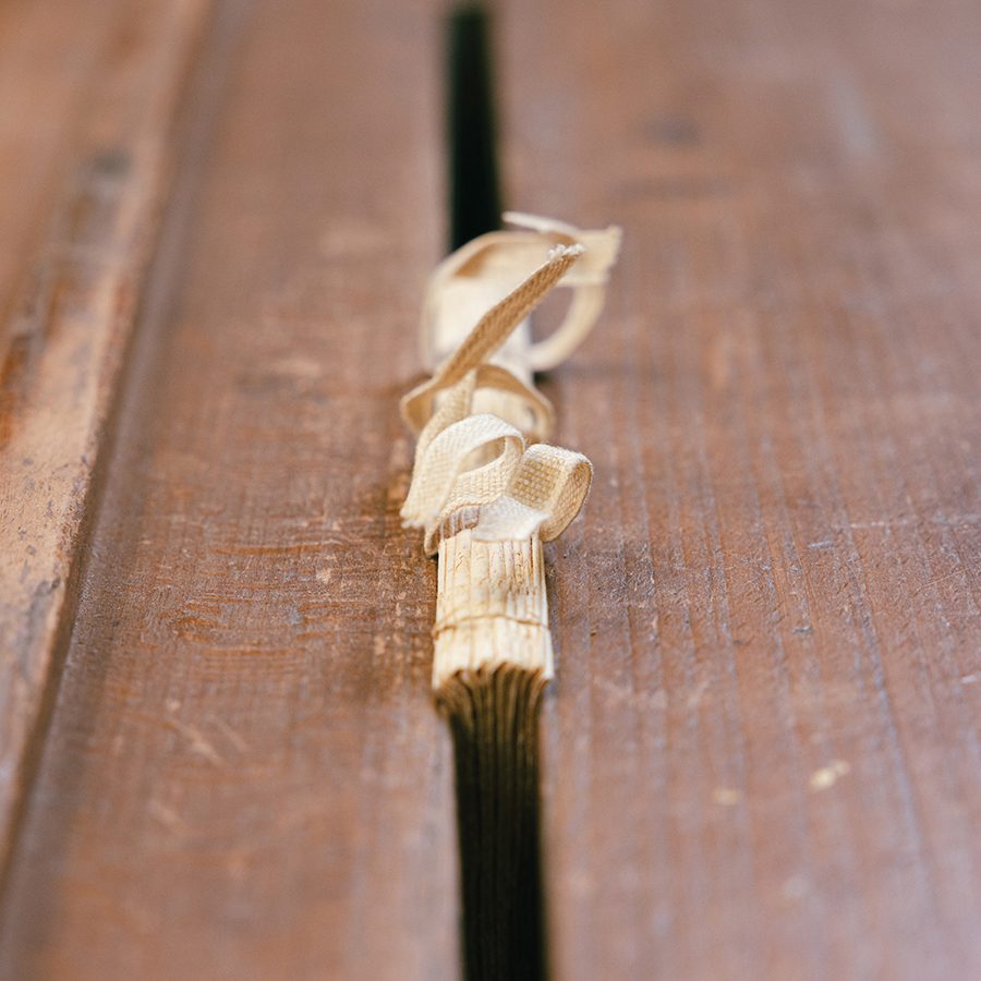 A close up of a book clamped on a wooden finishing press during the bookbinding process
