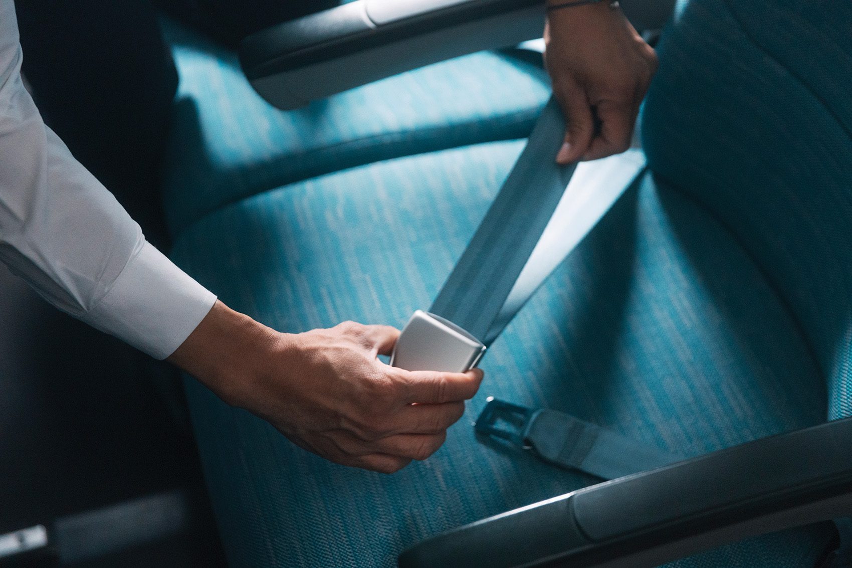 A pair of hands holding a seat belt on a Cathay Pacific flight