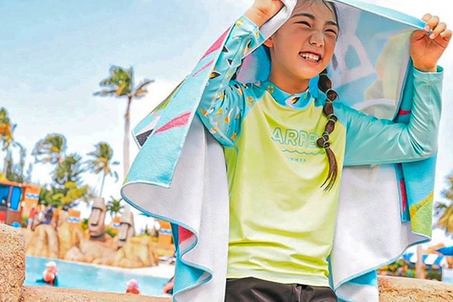  young girl, smiling, wearing a blue beach towel on her head on a sunny day 