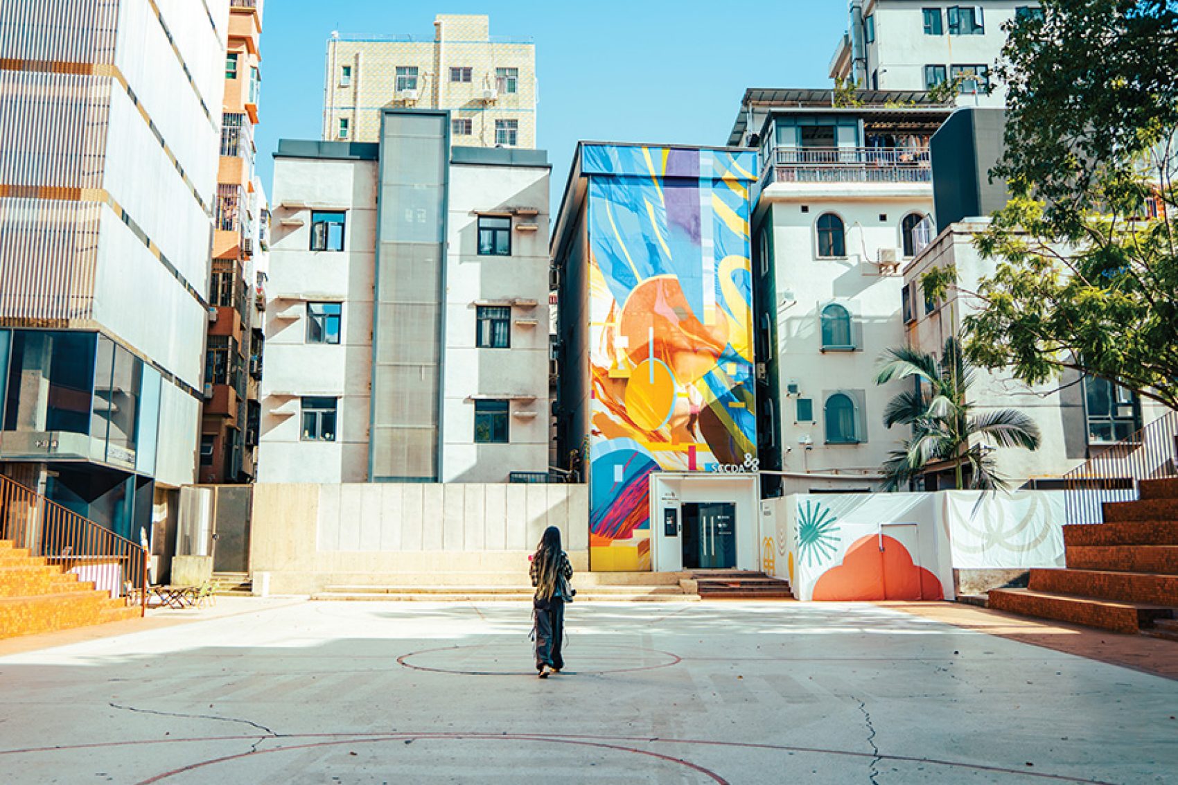 A woman standing outside apartment buildings and a colourful wall art in Nantou Ancient City