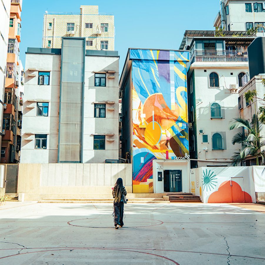 A woman standing outside apartment buildings and a colourful wall art in Nantou Ancient City
