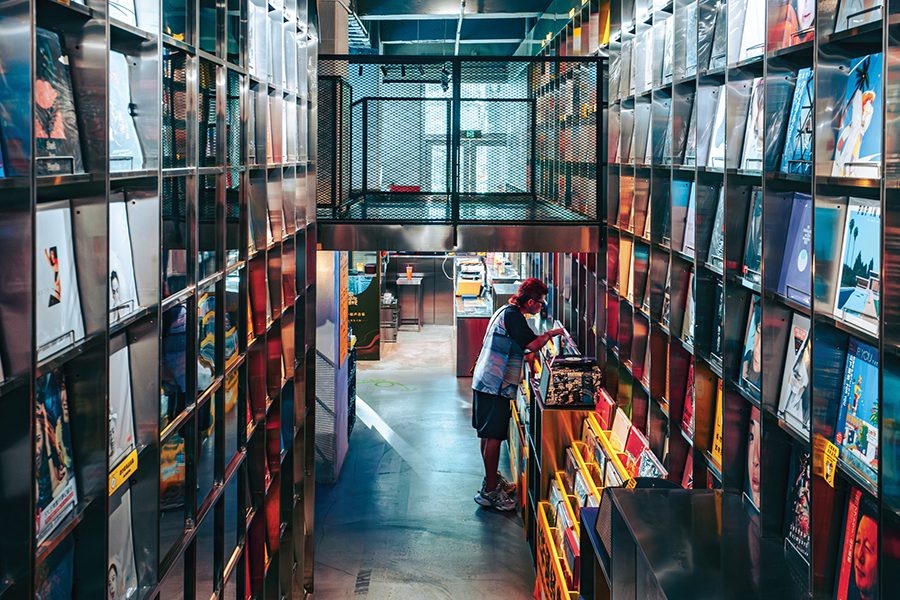 Walls full of vinyl records inside of shop HYM and a man browsing