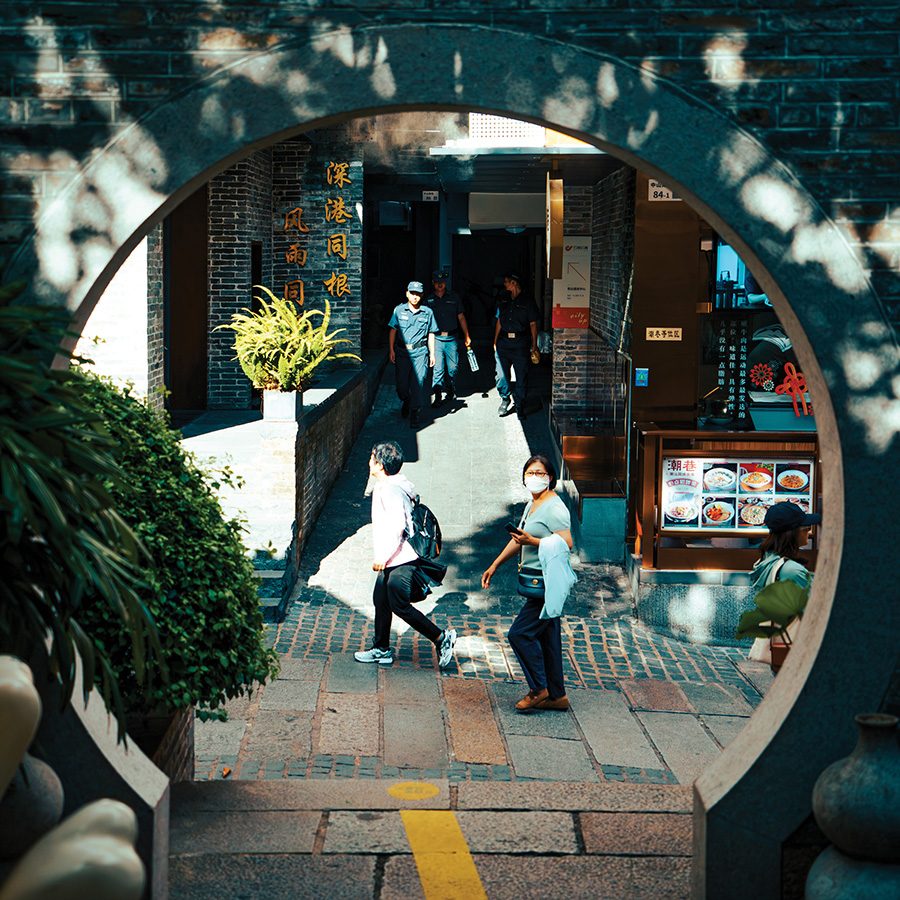 A street view of people walking around Nantou Ancient Town through a traditional Chinese moongate