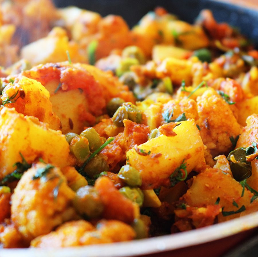 A close up of a steaming bowl of aloo gobhi in 