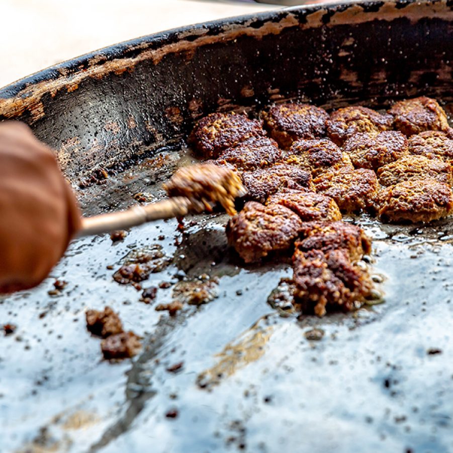 A street food vendor cooking Indian kakori and galauti kebabs in a largen pan