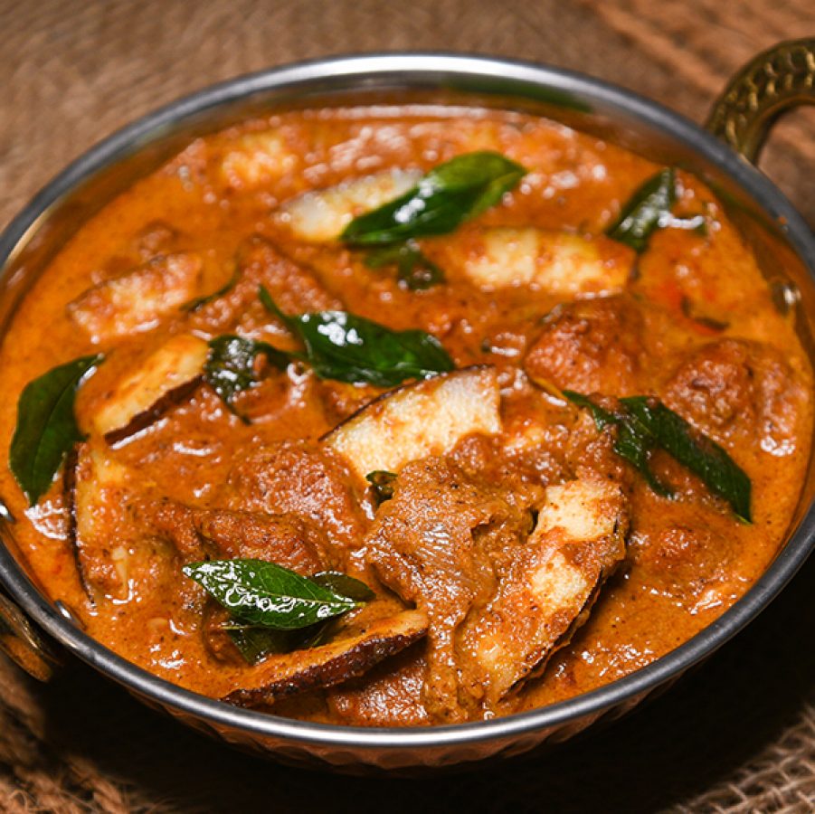 A close up of kosha mangsho mutton curry in a silver bowl on a brown dining cloth 