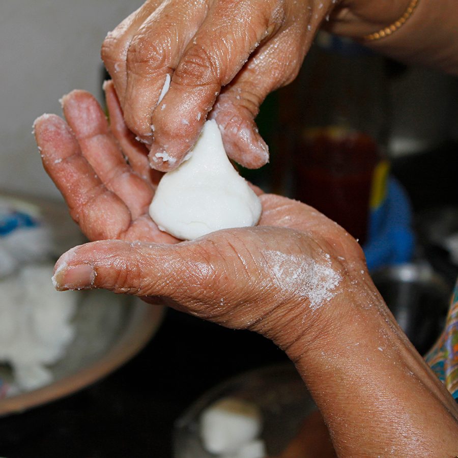 A closeup of a person making modak