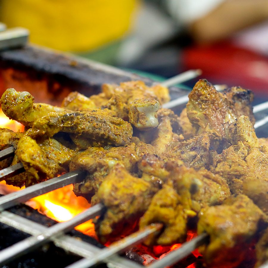A closeup of Indian kebab skewers over fire on a charcoal grill 