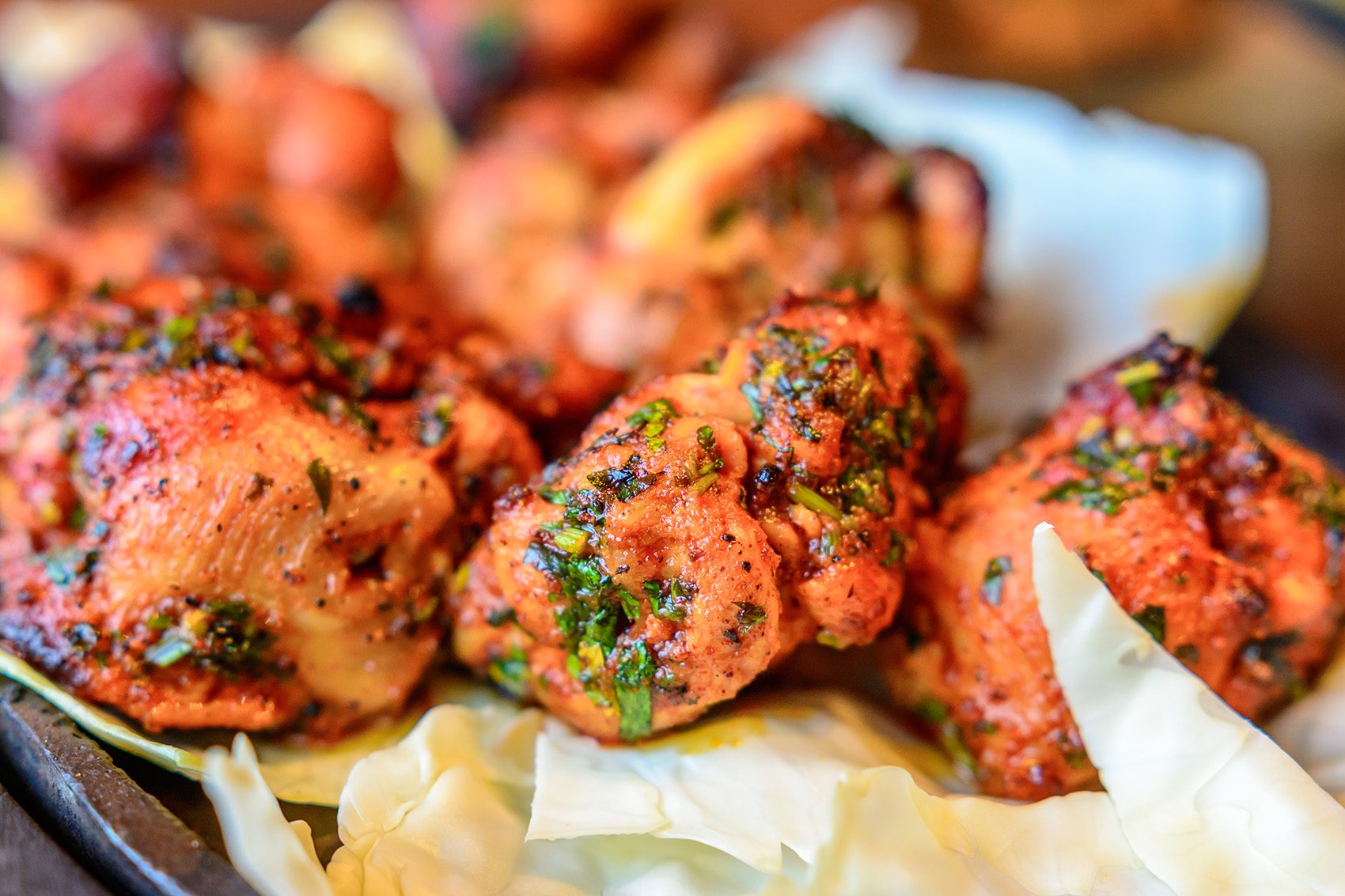A closeup of tandoori chicken on an iron plate