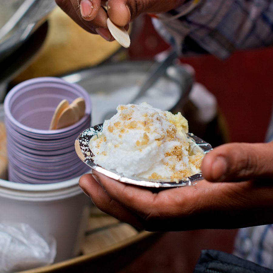 A closeup of a fluffy daulat ki chaat garnished with sugar, milk, saffron and nuts